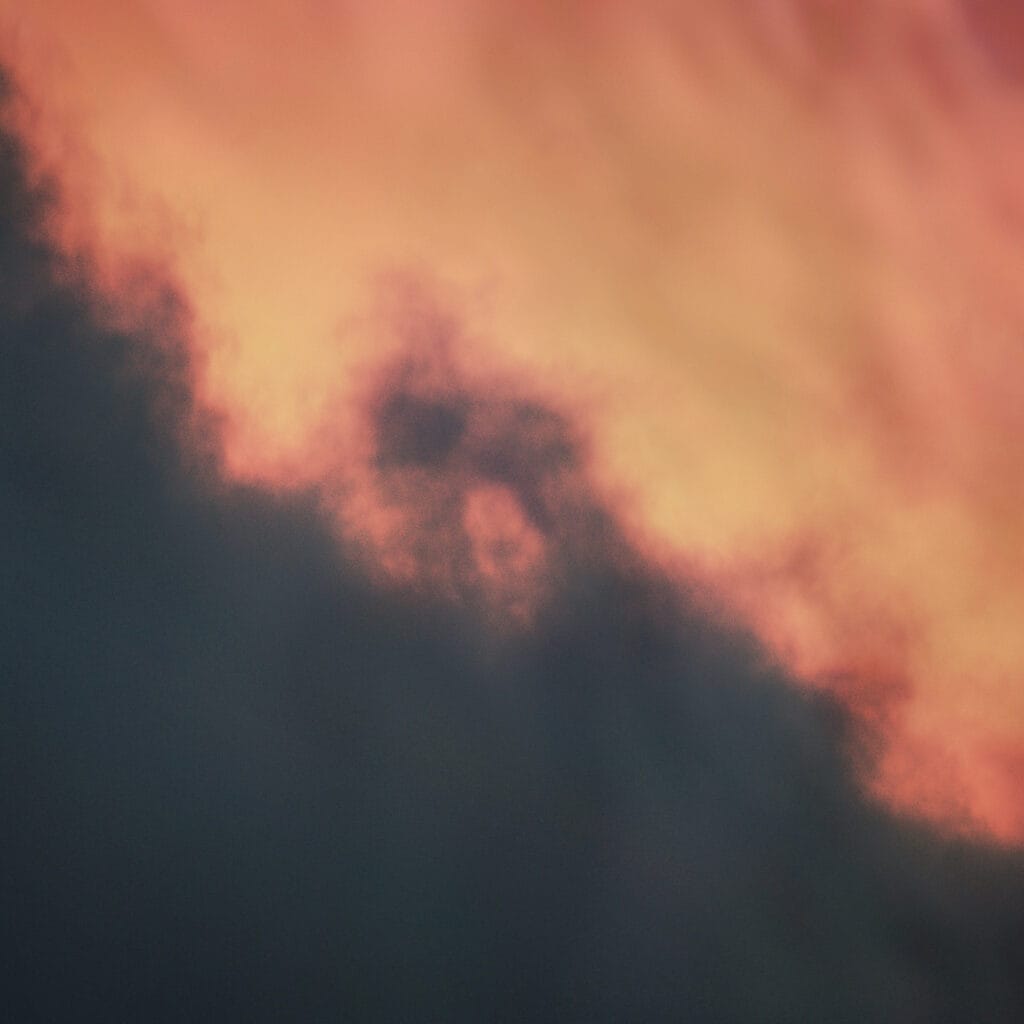 Album artwork for Anwei Huss 'Static' shows an orange and black sky, with dark clouds covering one half of the image and hazy orange glow from a sunset covering the other.
